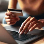 Pessoa digitando em laptop com cartão de crédito na mão, fazendo compra online.
