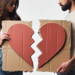 Casal segurando coração de papelão partido, simbolizando término de relacionamento.