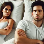 Casal na cama, distantes e de braços cruzados. Mulher olha para o lado, homem de olhos fechados.